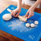 Person rolling dough on a blue baking mat with measurements